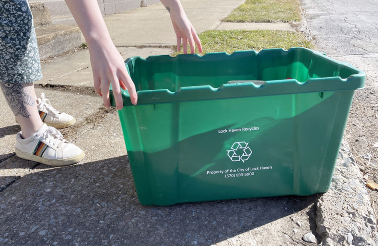 person putting out their recycling bin to the curb