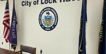 image showing the City of Lock Haven Council chambers with the Wall that says City of Lock Haven, the City of Lock Haven seal, and an American Flag, City of Lock Haven Flag, Clinton County flag, and Commonwealth of Pennsylvania flag